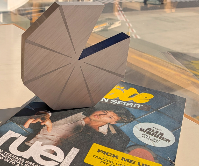 A wooden Pac-Man style geometric trophy sitting on top of a printed Teen Spirit music magazine featuring Ruel on the cover.